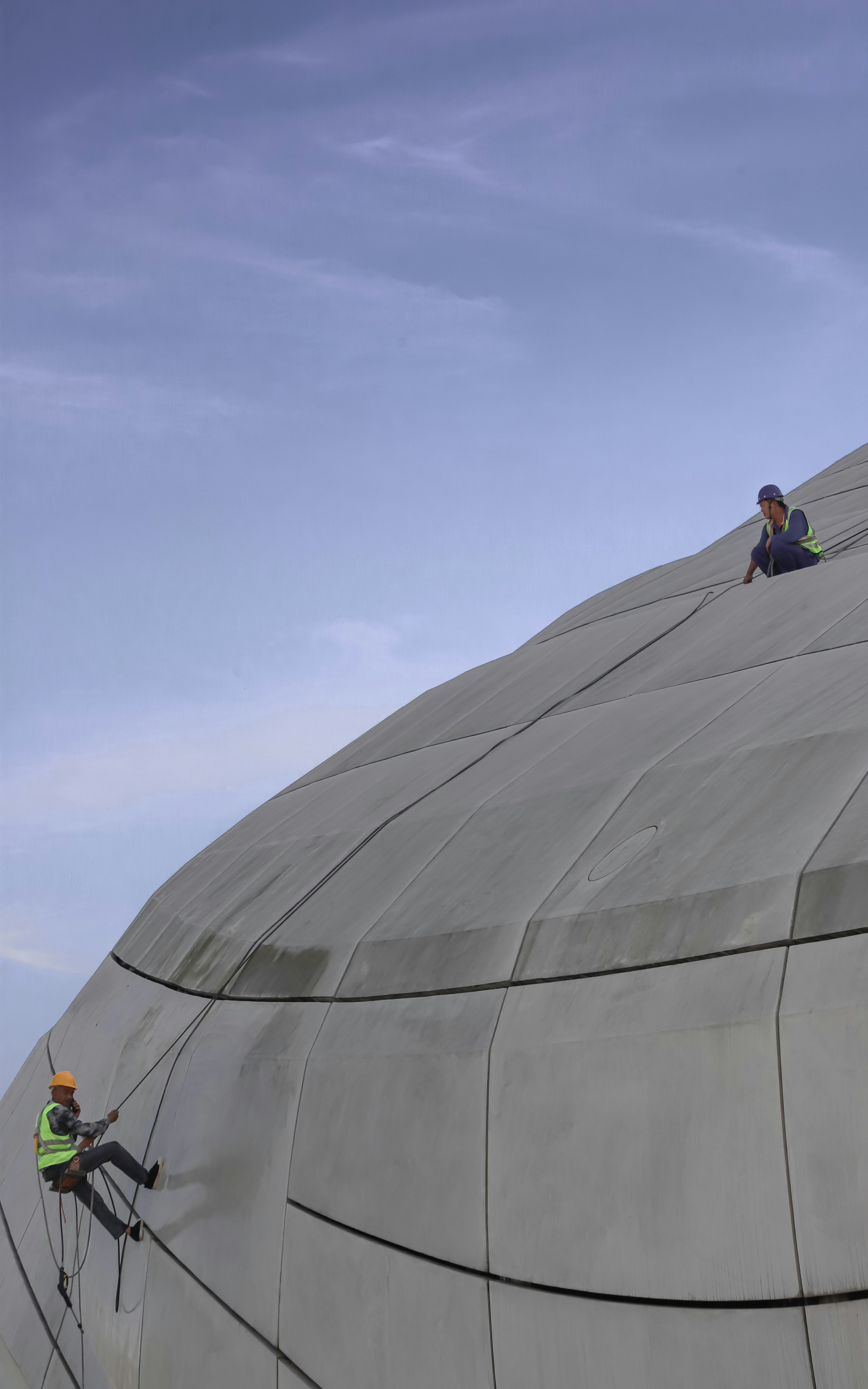 man in black jacket standing on gray round roof during daytime